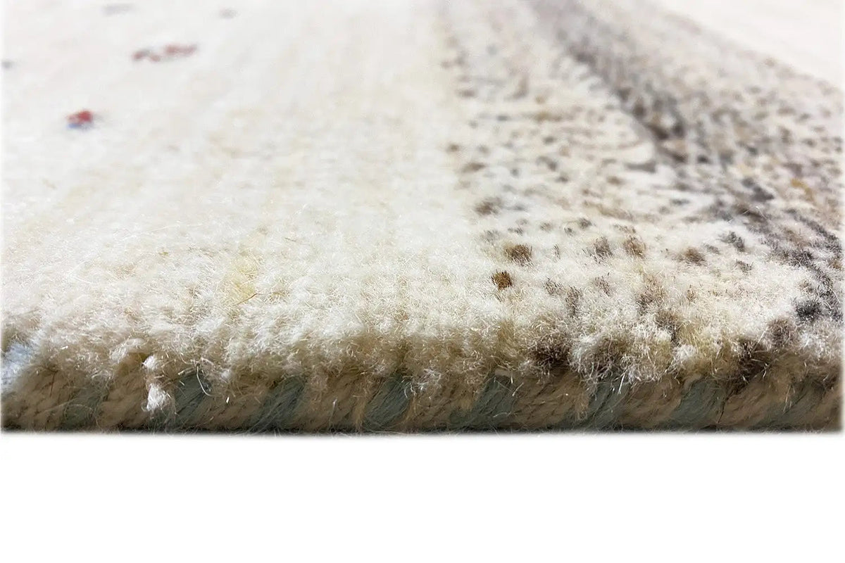 Close-up of a Gabbeh-Lori rug edge with short fringes, beige pile with colorful dots.