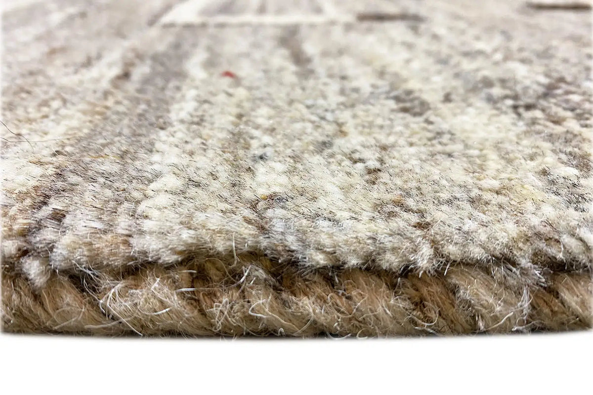 Close-up: rug pile with short fibers and a bound edge, light beige-gray mottled texture