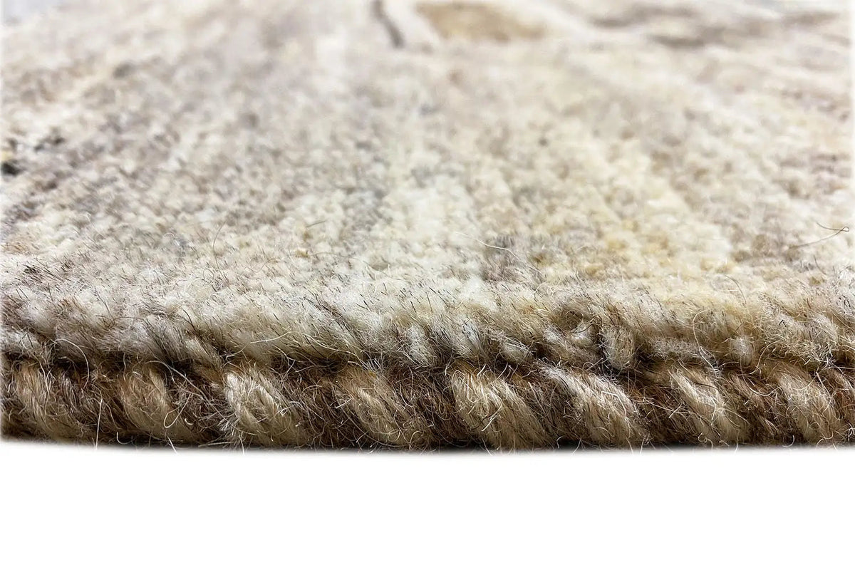 Gabbeh rug close-up of the pile: dense, beige-brown wool pile with a visible edge