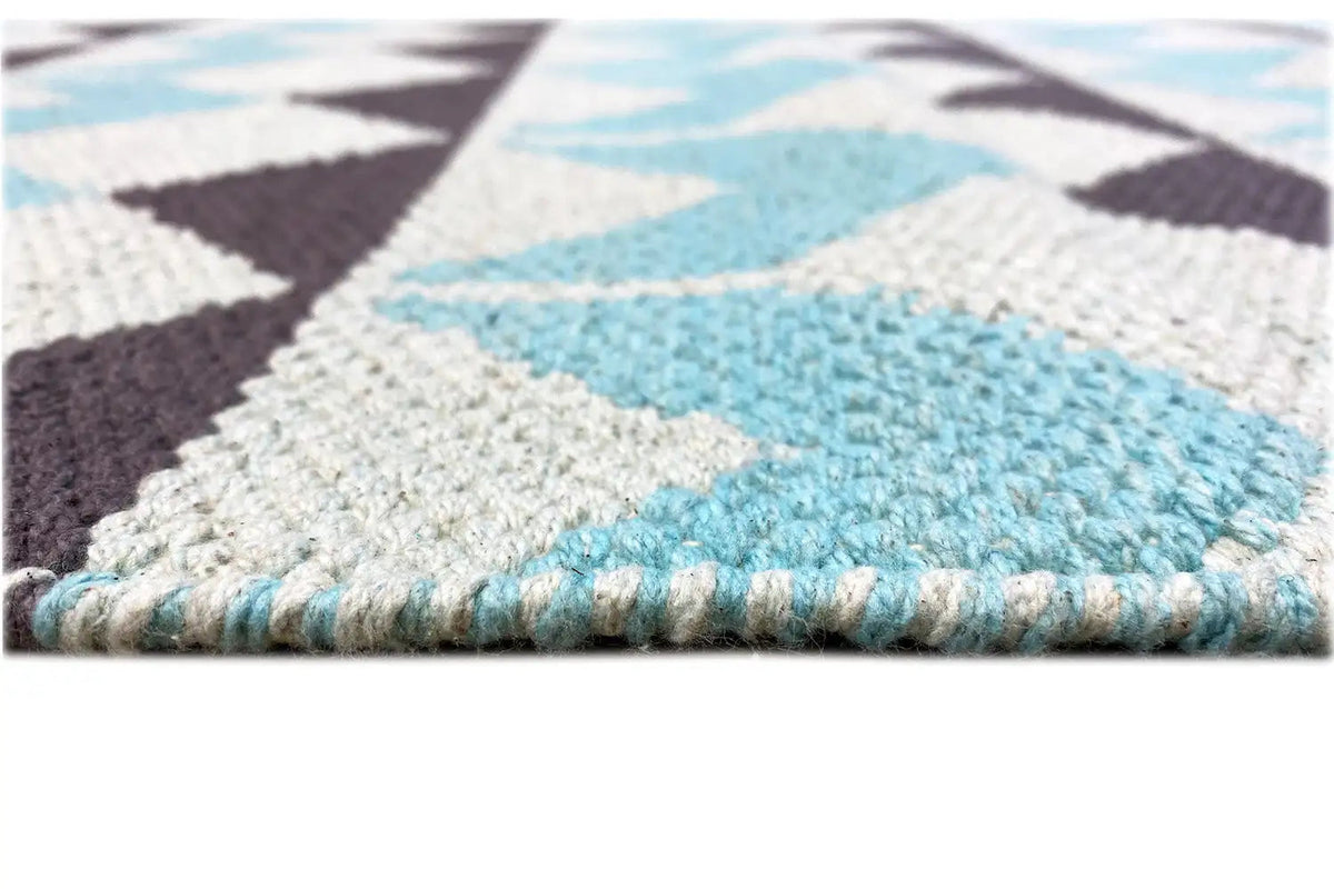 Close-up of a kilim rug: woven surface with a colored edge and short fringes