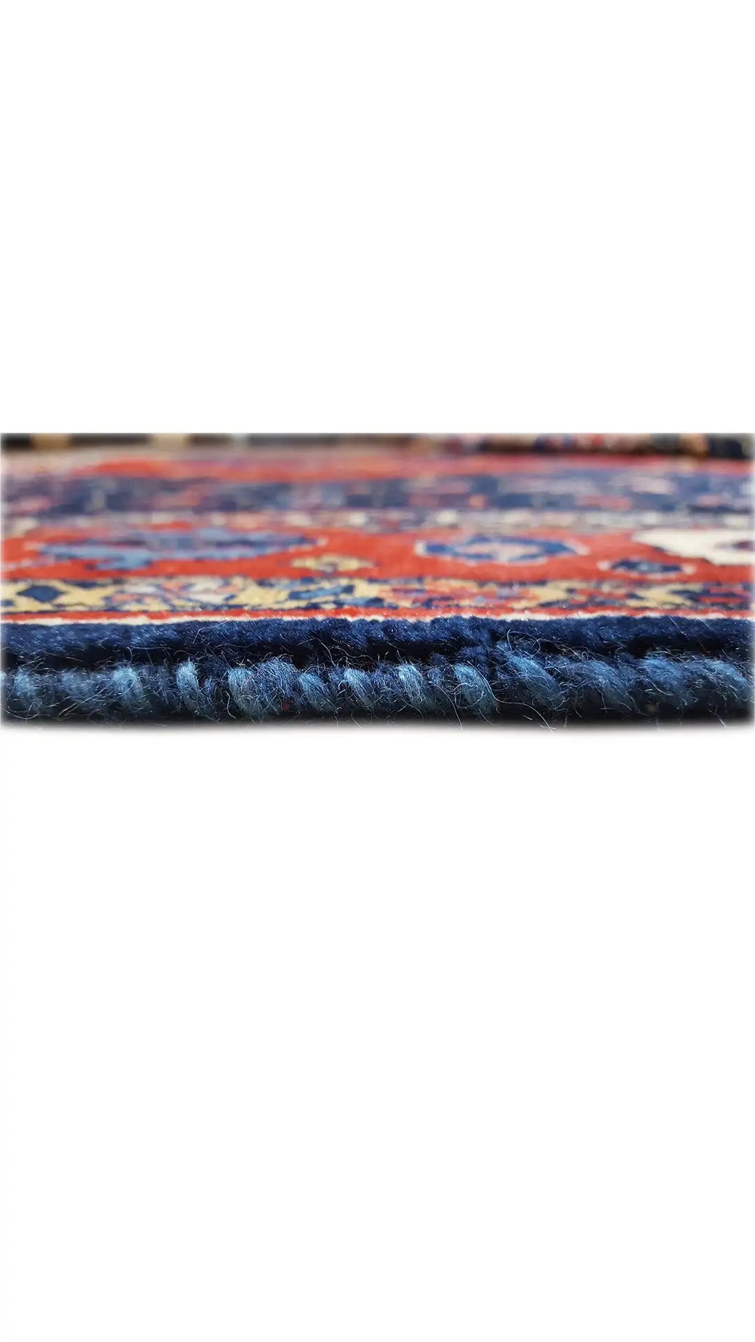 Close-up of the carpet edge with short fringes and a blue-red ornamental pattern
