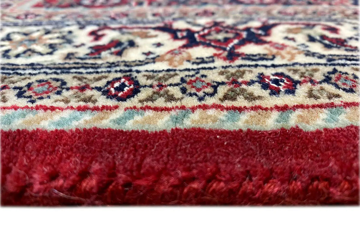 Carpet edge with fringe and dense pile; red-backed border in detail.