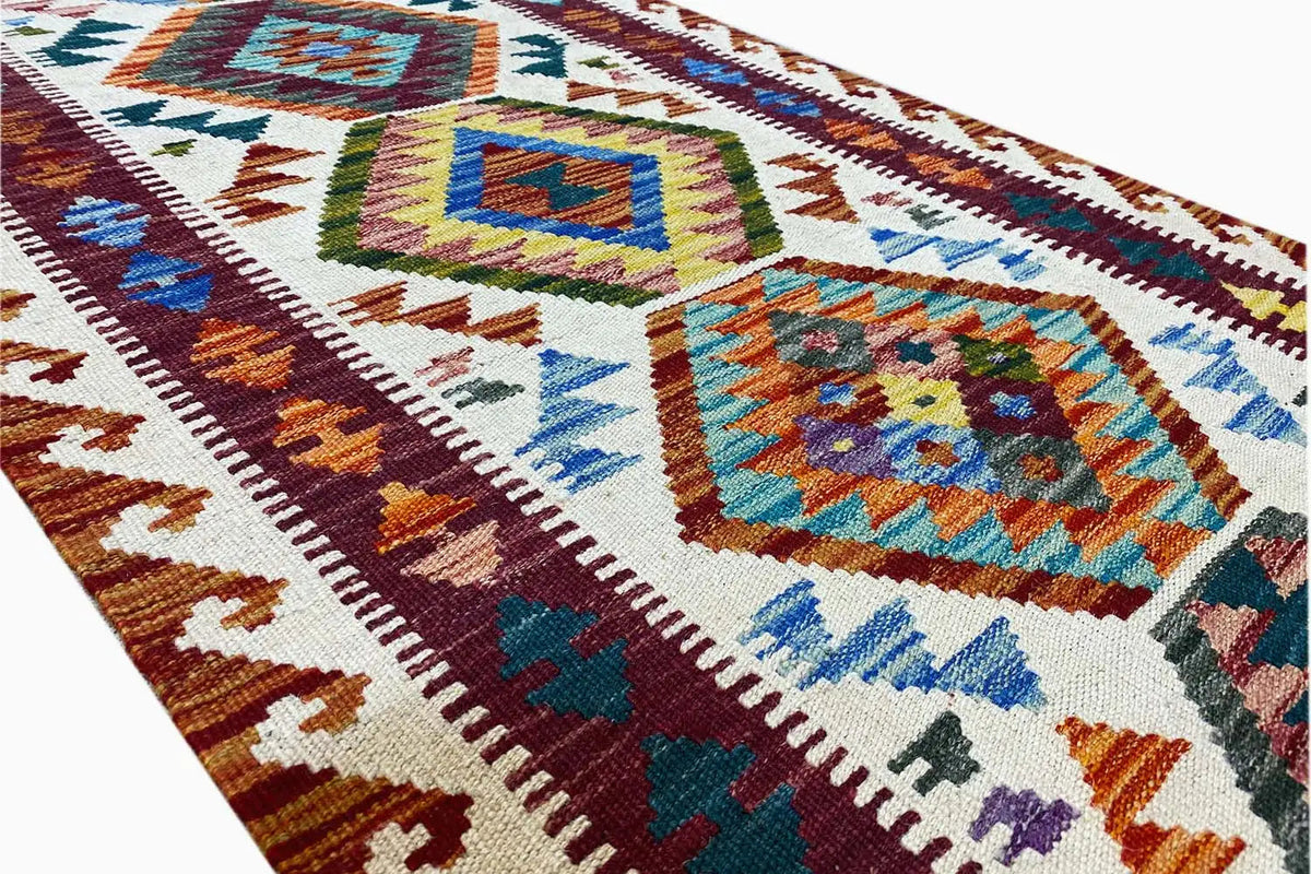 Kilim runner detail with colorful diamonds, decorative trim, and a densely woven texture