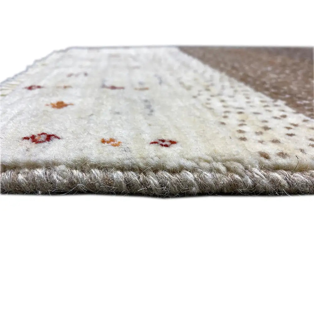 Gabbeh rug detail with fringes, a cream-colored surface, and colorful ornaments