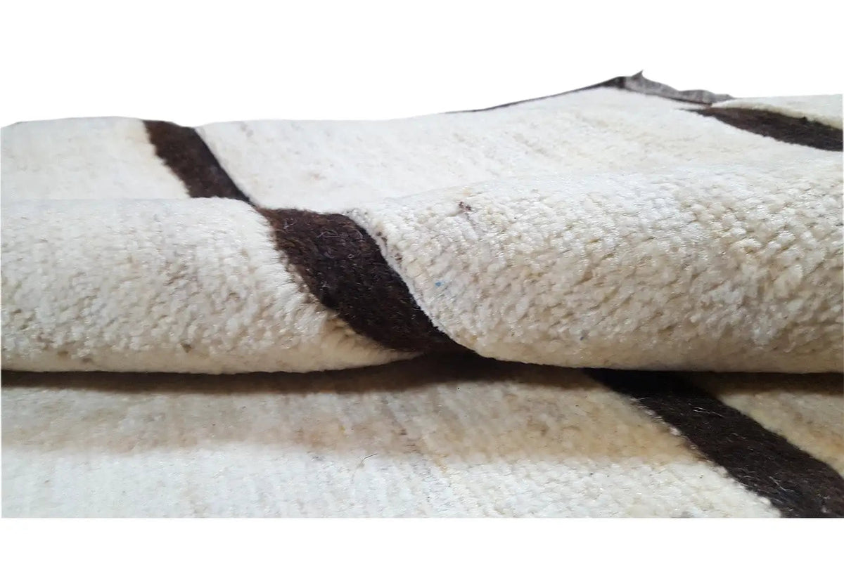Gabbeh rug detail: beige pile with dark stripes and a knotted surface