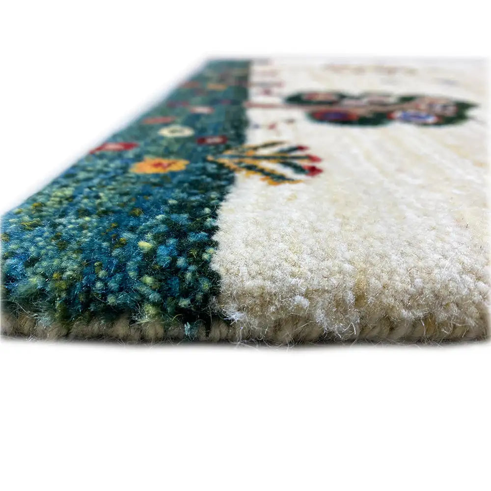 Gabbeh rug detail view: beige pile with a dark green patterned stripe and dense wool texture.