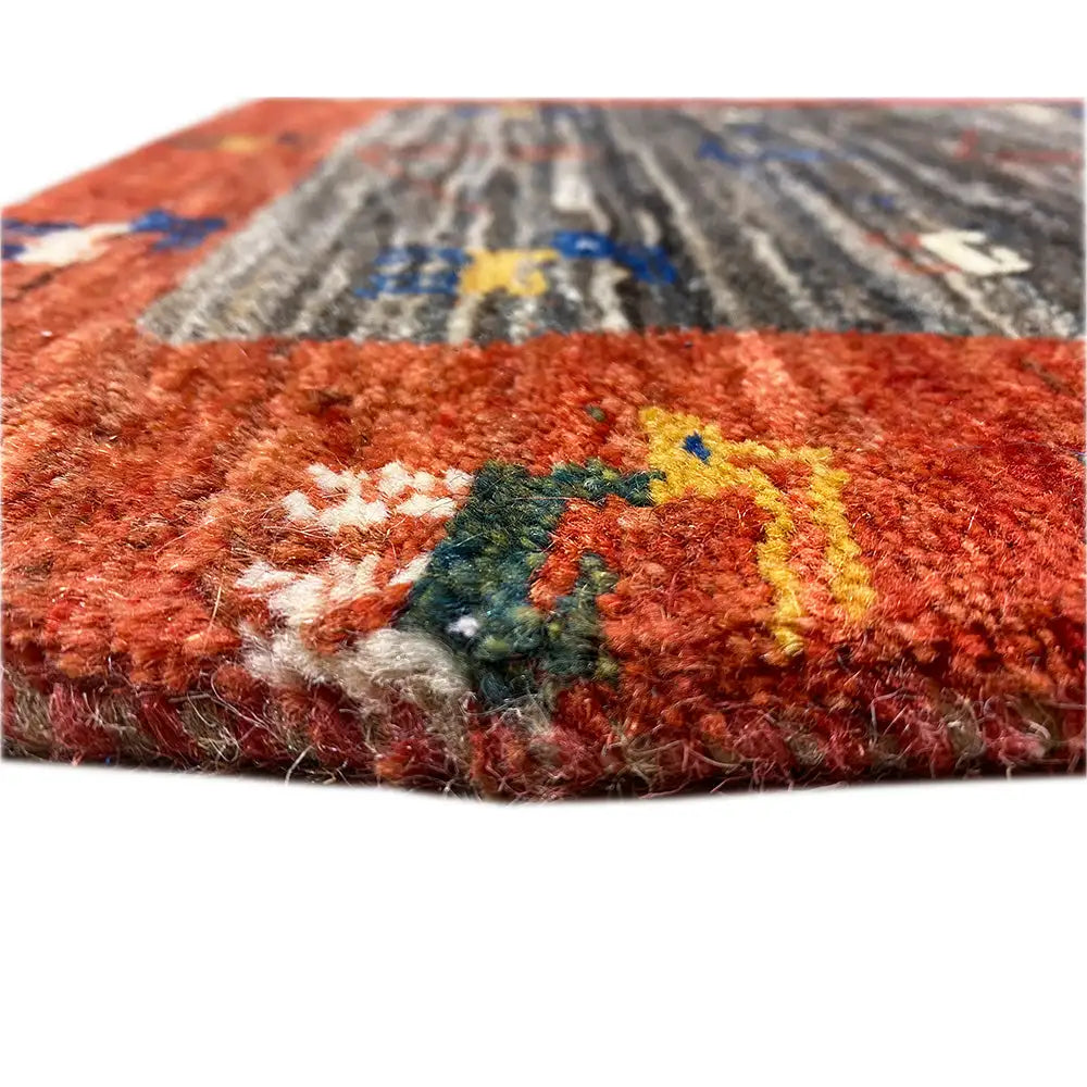 Gabbeh rug close-up: reddish-brown wool fibers with colorful pattern details