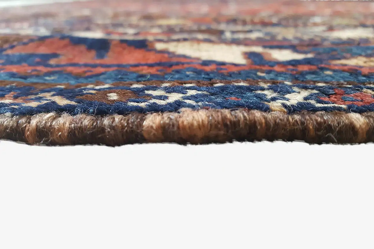 Carpet edge with dense pile and brown border, multicolored pattern in close-up detail