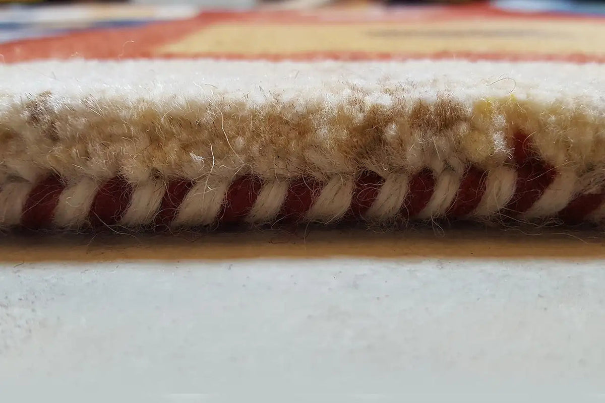 Rug fringe along the edge, twisted yarn in red, dark blue and beige