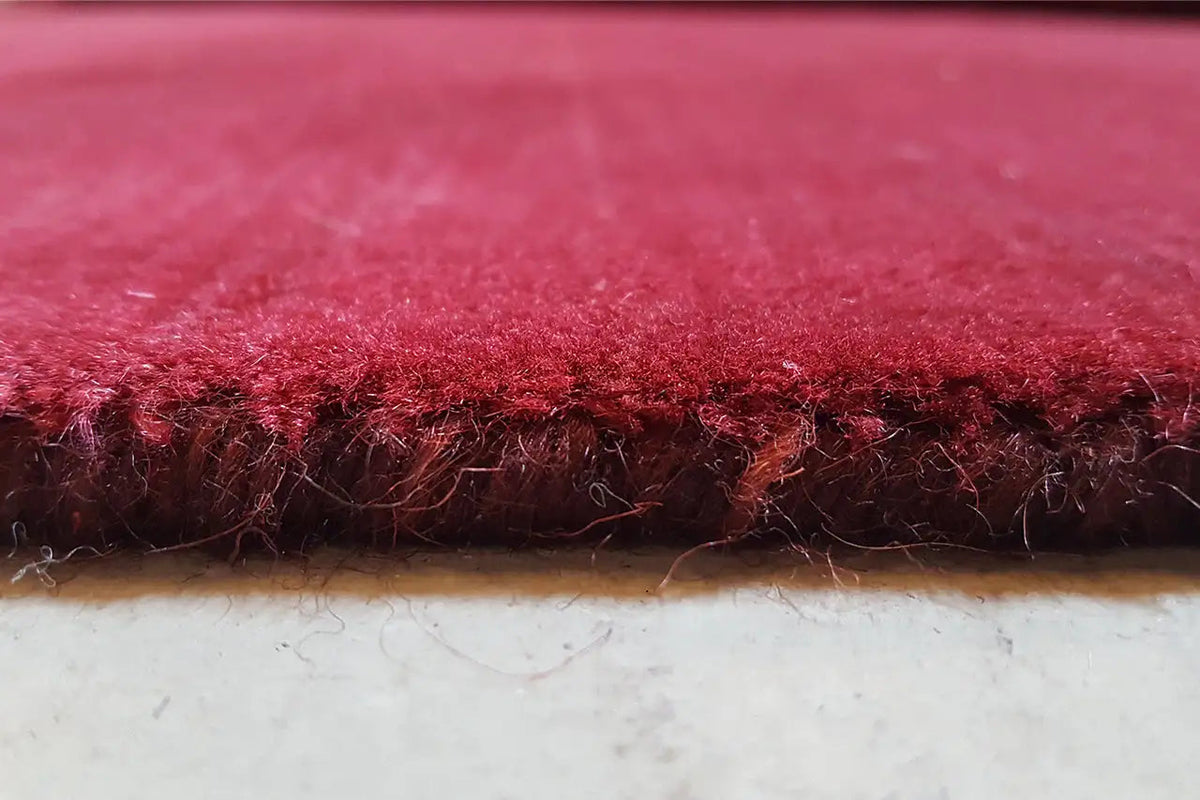 Gabbeh rug edge close-up: short pile and visible edge, burgundy