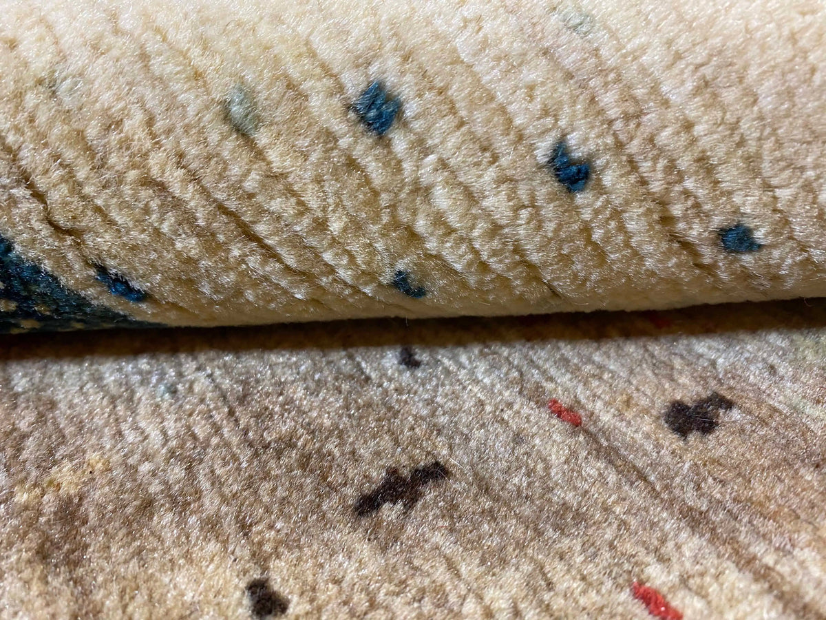 Gabbeh Lori rug detail: beige pile with small blue and red ornaments