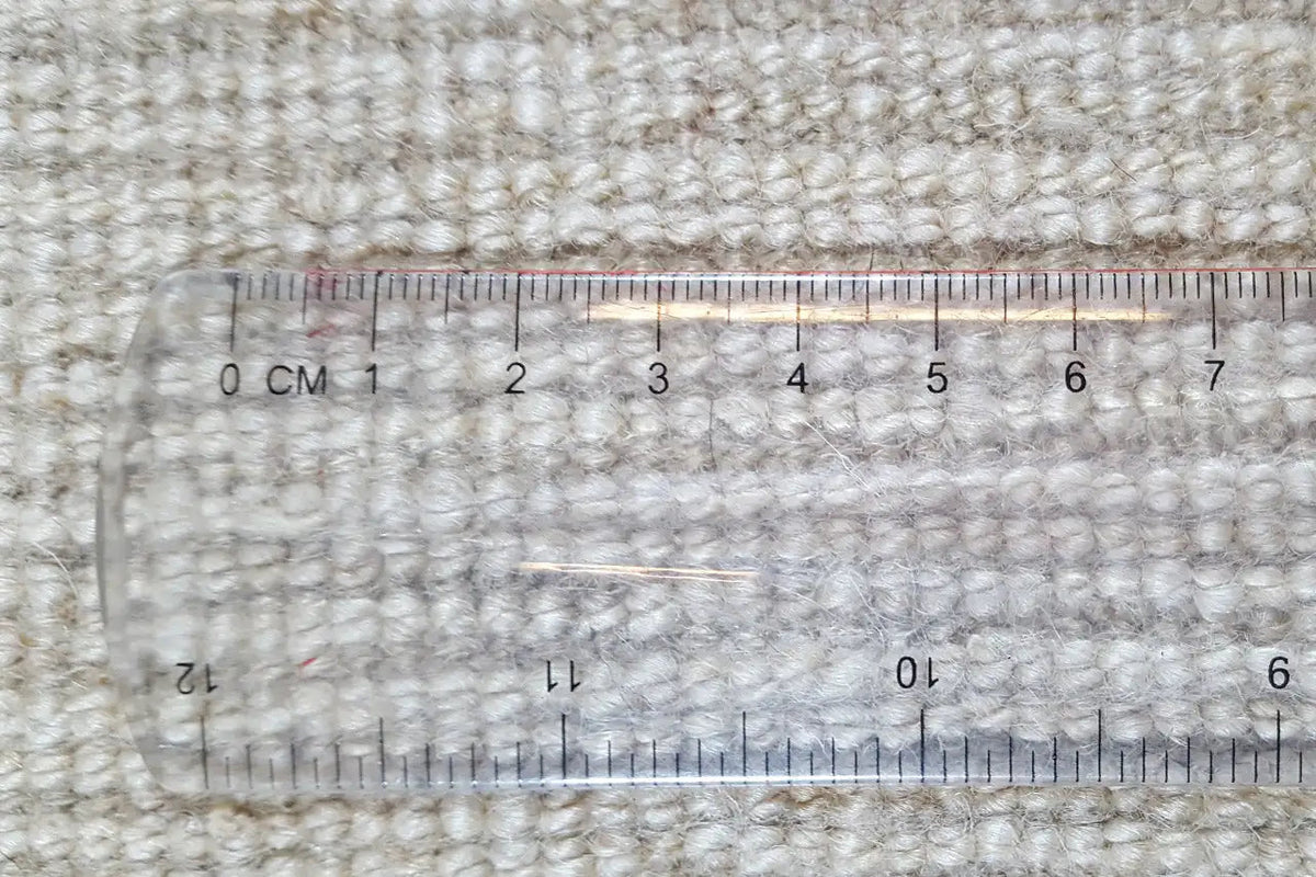 Gabbeh rug with tape measure: dense weave, beige color, low-pile texture.