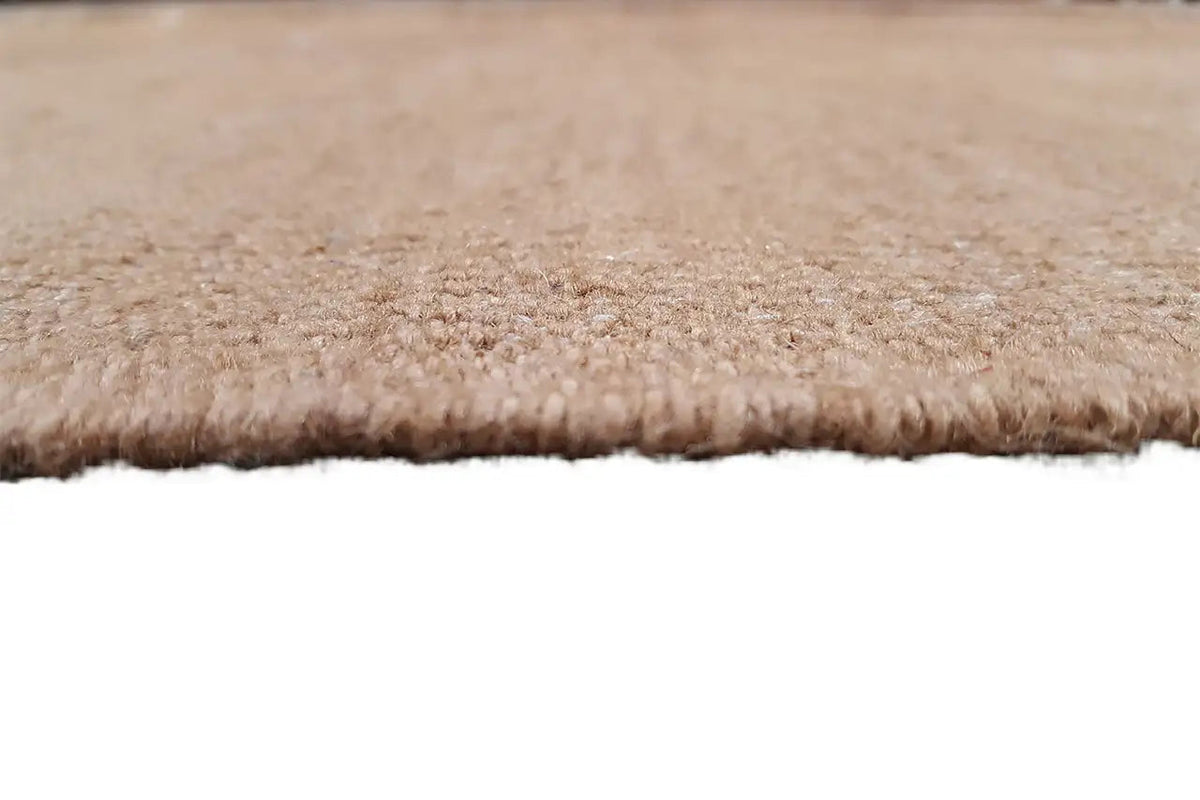 Close-up: uniform beige fabric pile texture with a short frayed edge