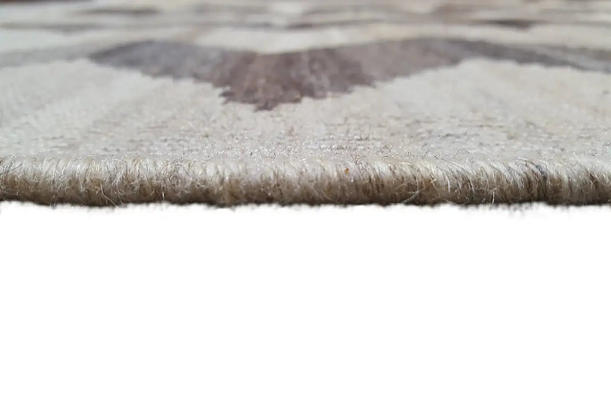 Kilim rug edge with short fringes, light woven surface, gray-brown pattern.