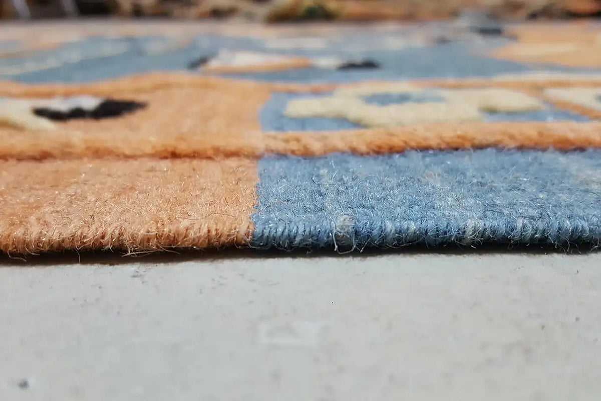 Close-up of the edge of a kilim rug with fringes, blue and beige woven pattern