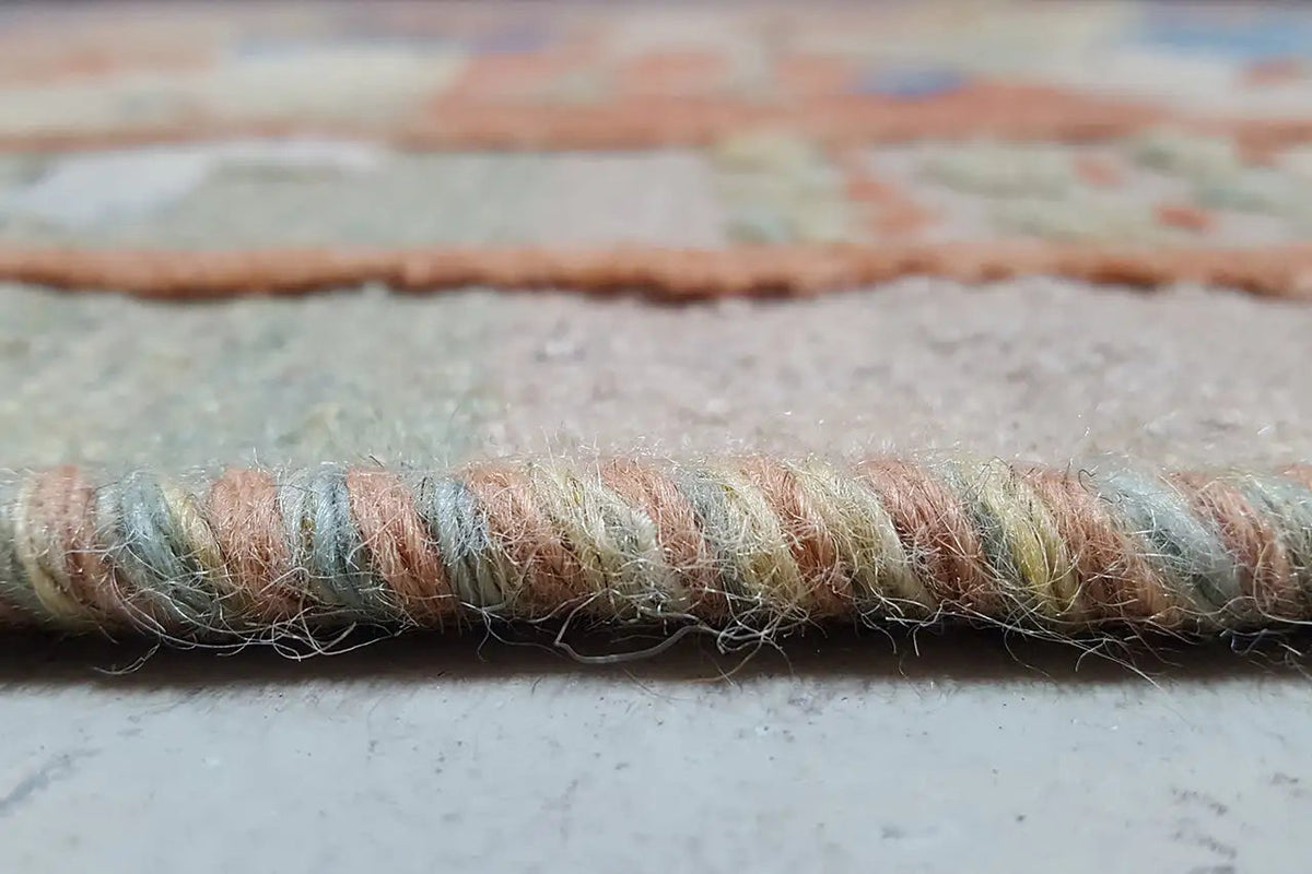 Close-up: carpet edge with natural fringes and a twisted woven border
