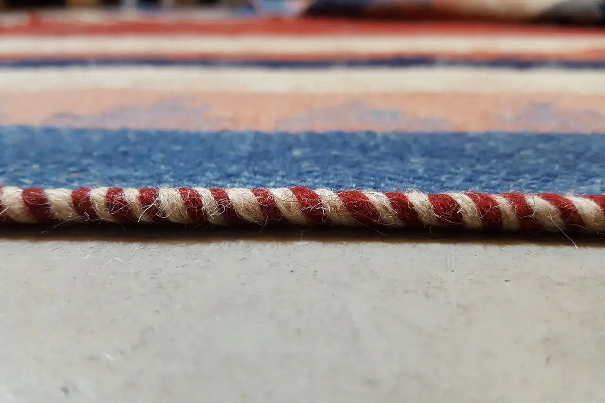 Carpet edge with decorative fringe in red, cream and blue
