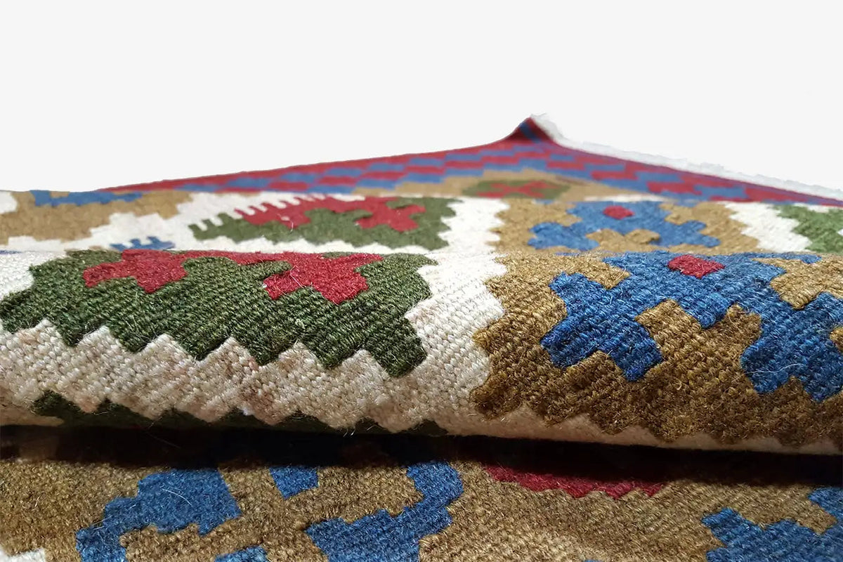Close-up of the kilim fabric with multicolored cross and diamond motifs.