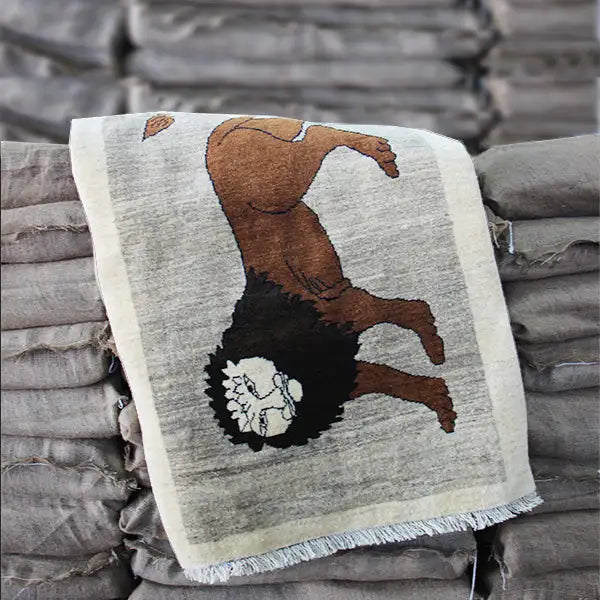 Gabbeh rug with a lion motif, draped over a blanket; beige background, brown animal
