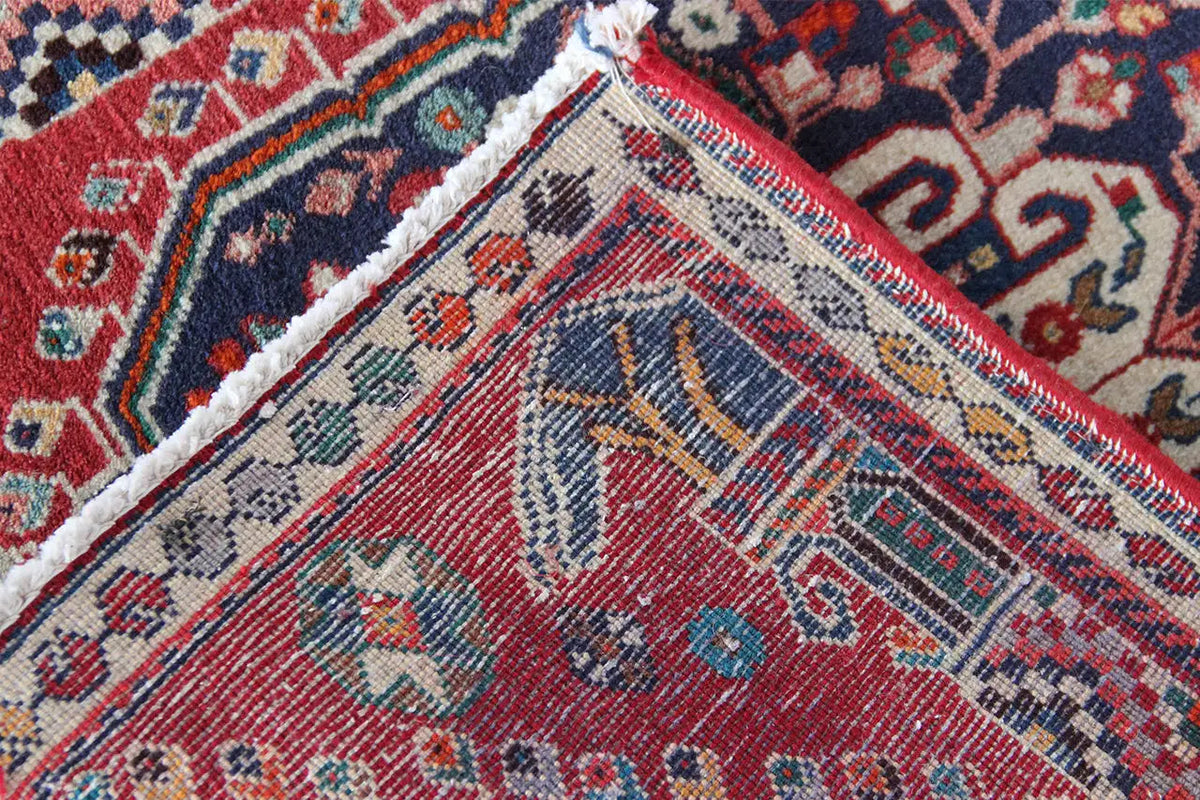Oriental rug corner with a woven texture, red and blue patterns, and a visible border