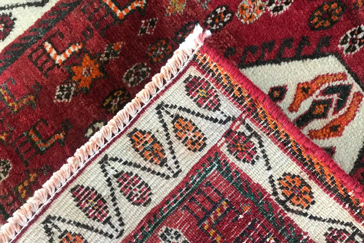 Carpet detail with red pattern, woven border, and fringe