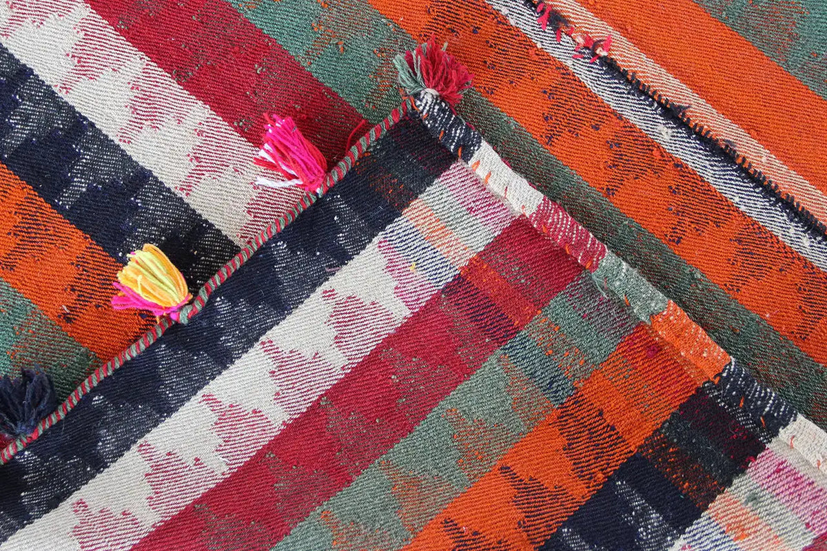 Jajim rug detail with diagonal stripes and shiny threads, tassel along the edge.