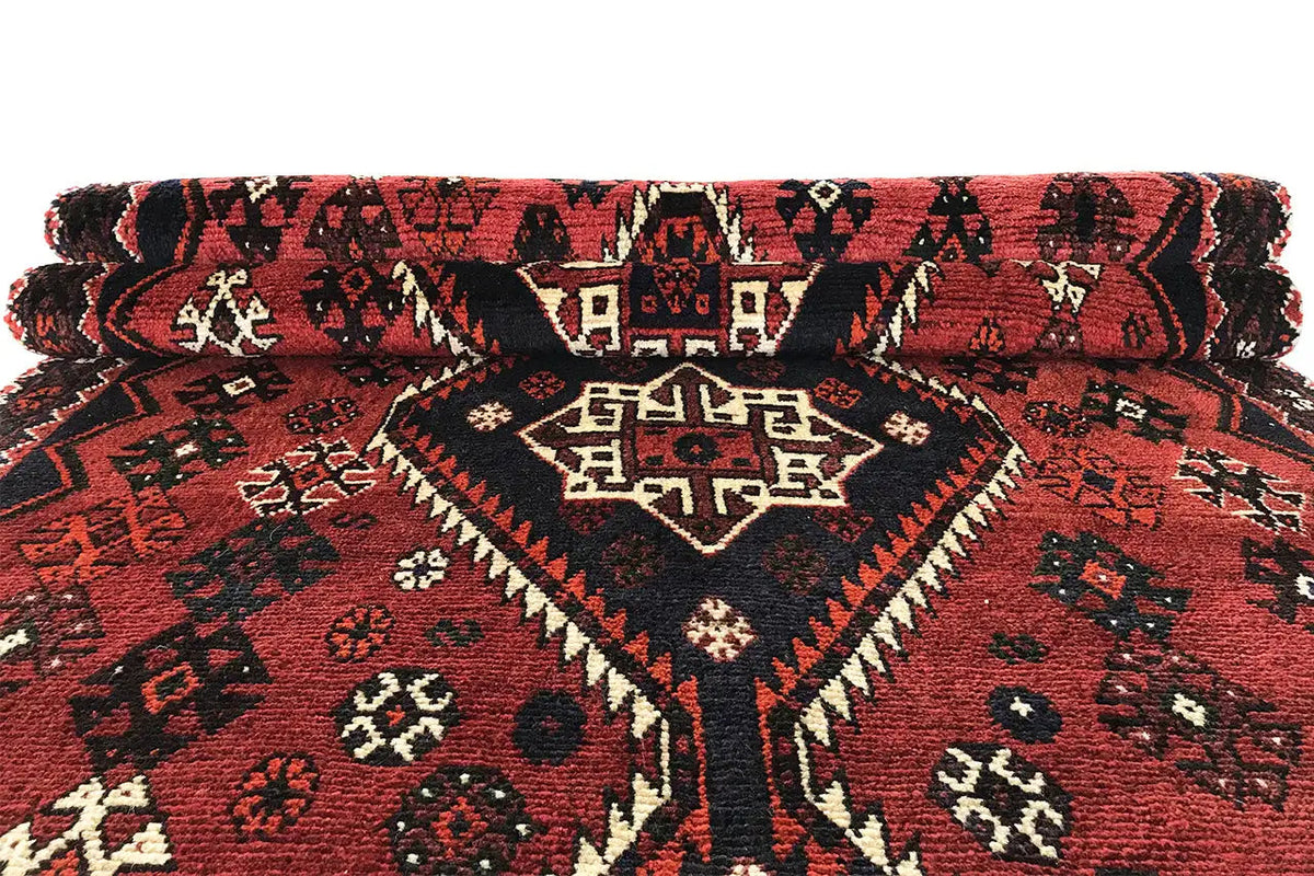 Rolled-up runner: red ornamental pattern with a dark border and fringes