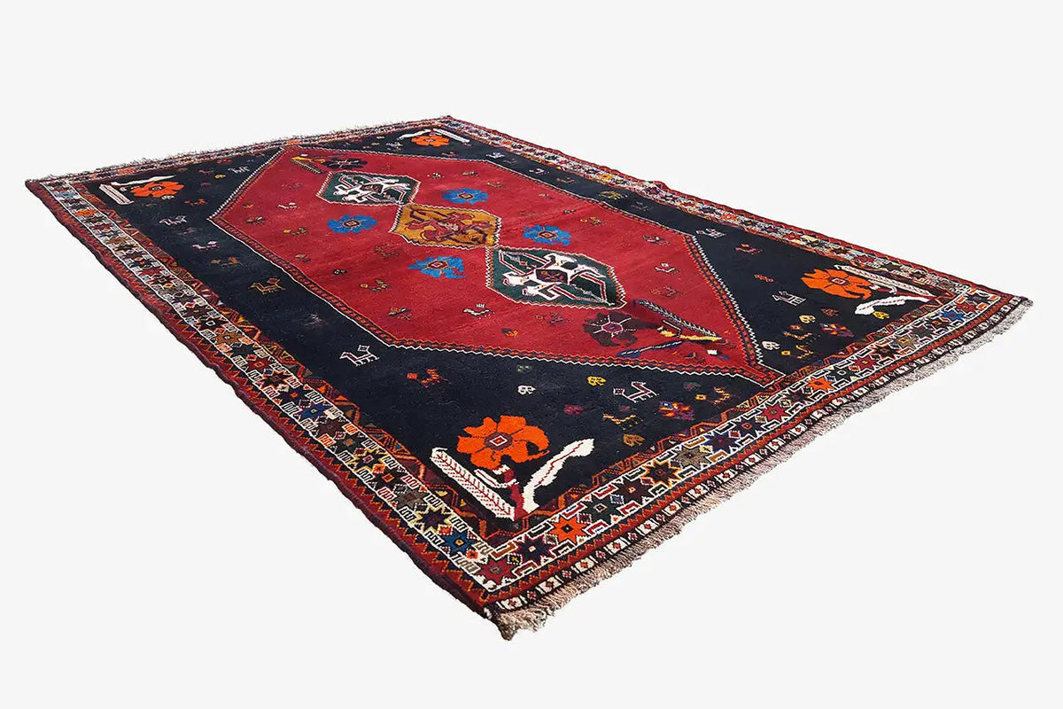 Oriental rug with a red center, dark blue border, and colorful figurative ornaments
