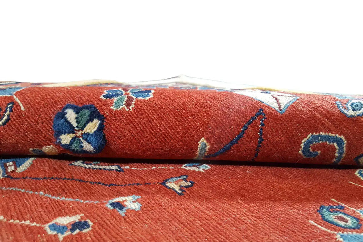 Close-up: red rug with blue-beige floral patterns and fringes