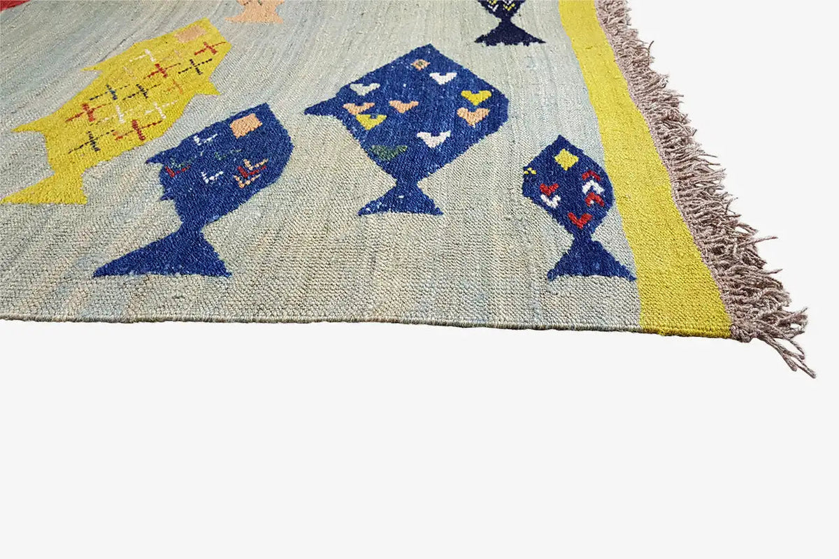 Kilim corner with fish motifs in blue, yellow, and red, with fringes along the edge