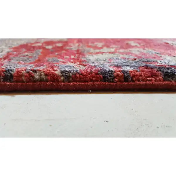 Carpet edge with dense pile, color transitions from red, gray, and blue