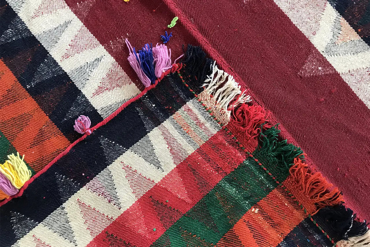 Jajim rug detail: red and dark blue stripes with frayed edges and yarn tassels