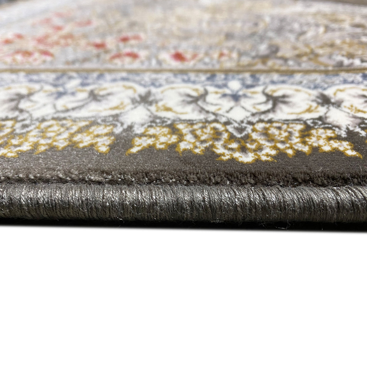 Smoke-gray carpet in detail: cloth edge with short fringes and a patterned upper edge.