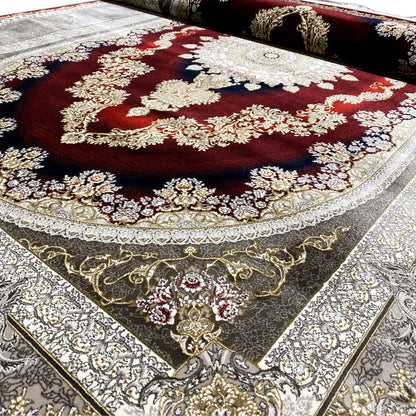 Detail view of an Oriental rug with a red center, silver borders, and gold ornaments