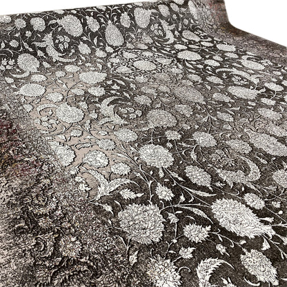 Close-up of a velour rug: silver floral ornament on a dark background