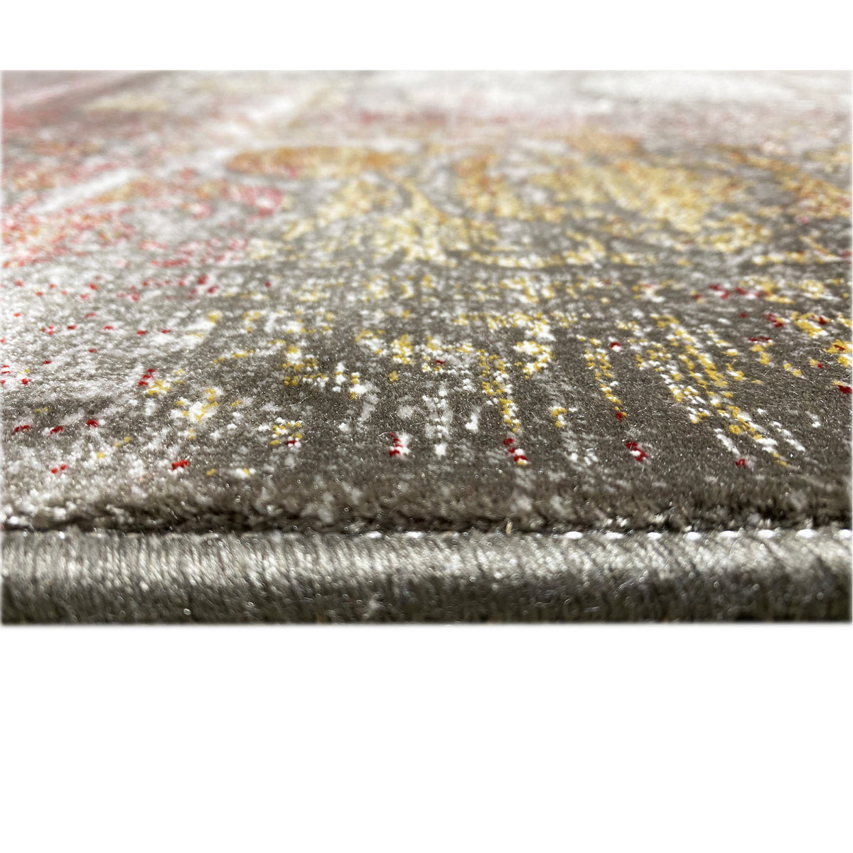 Carpet detail at the edge: tassels, a silvery-gray floral pattern with golden-brown speckles