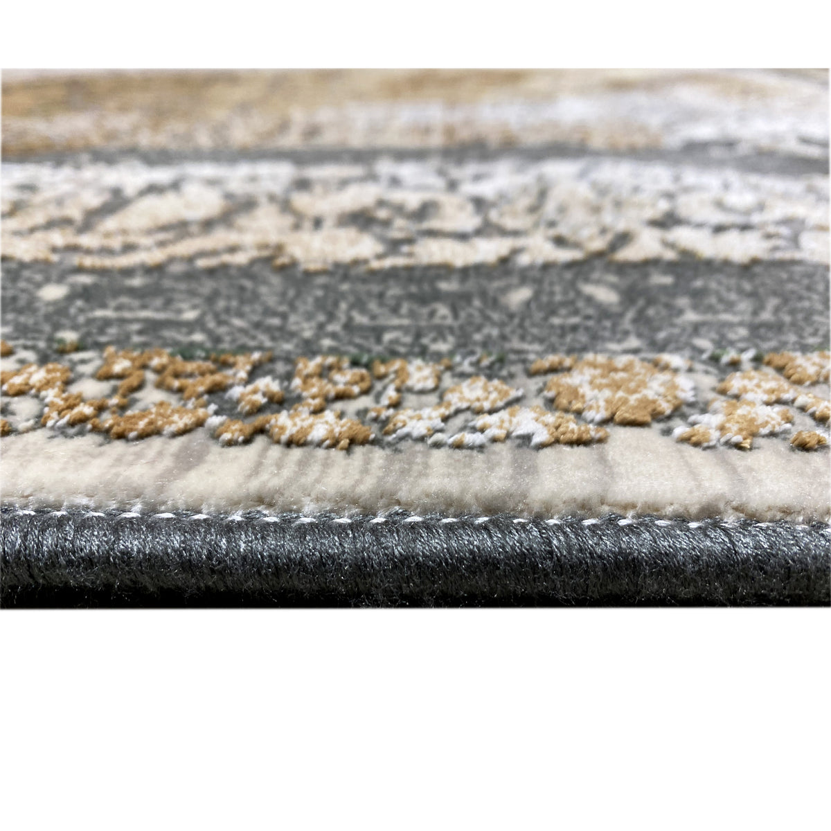 Carpet edge with a fine pile and bound border; pattern in beige, silver, and dark gray.
