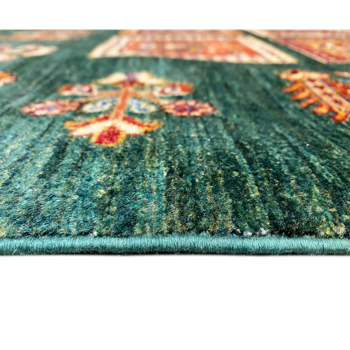 Close-up of the Khorjin carpet: green pile surface with colorful square ornaments