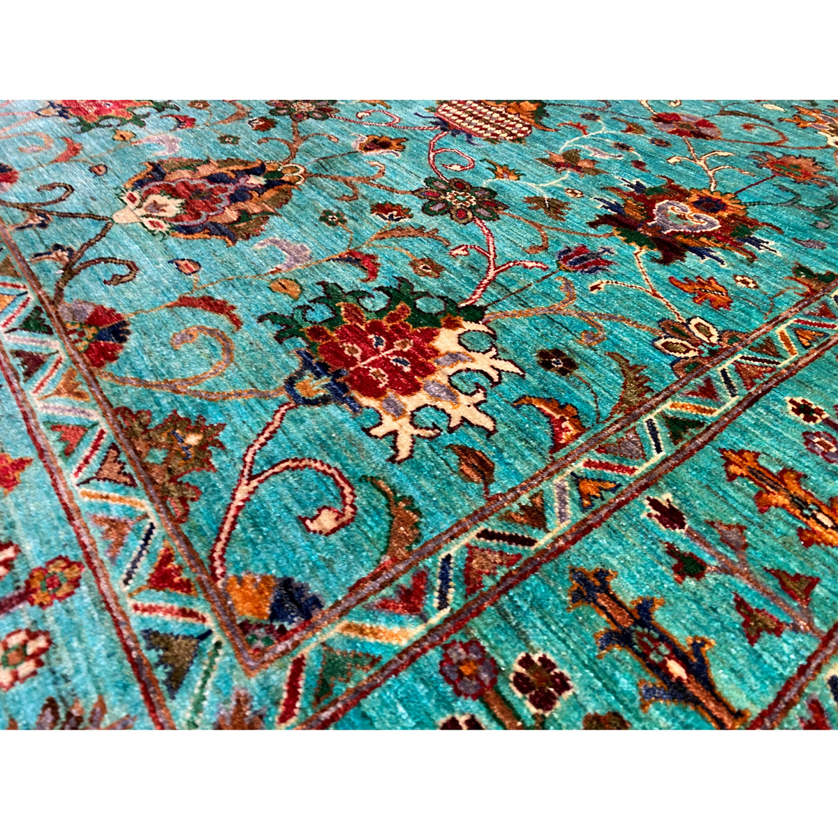 Detail view of the turquoise Khorjin rug: floral pattern with colorful flowers