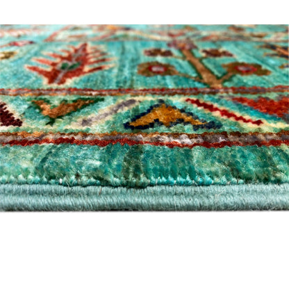 Close-up of the carpet edge with turquoise pile and multicolored patterns
