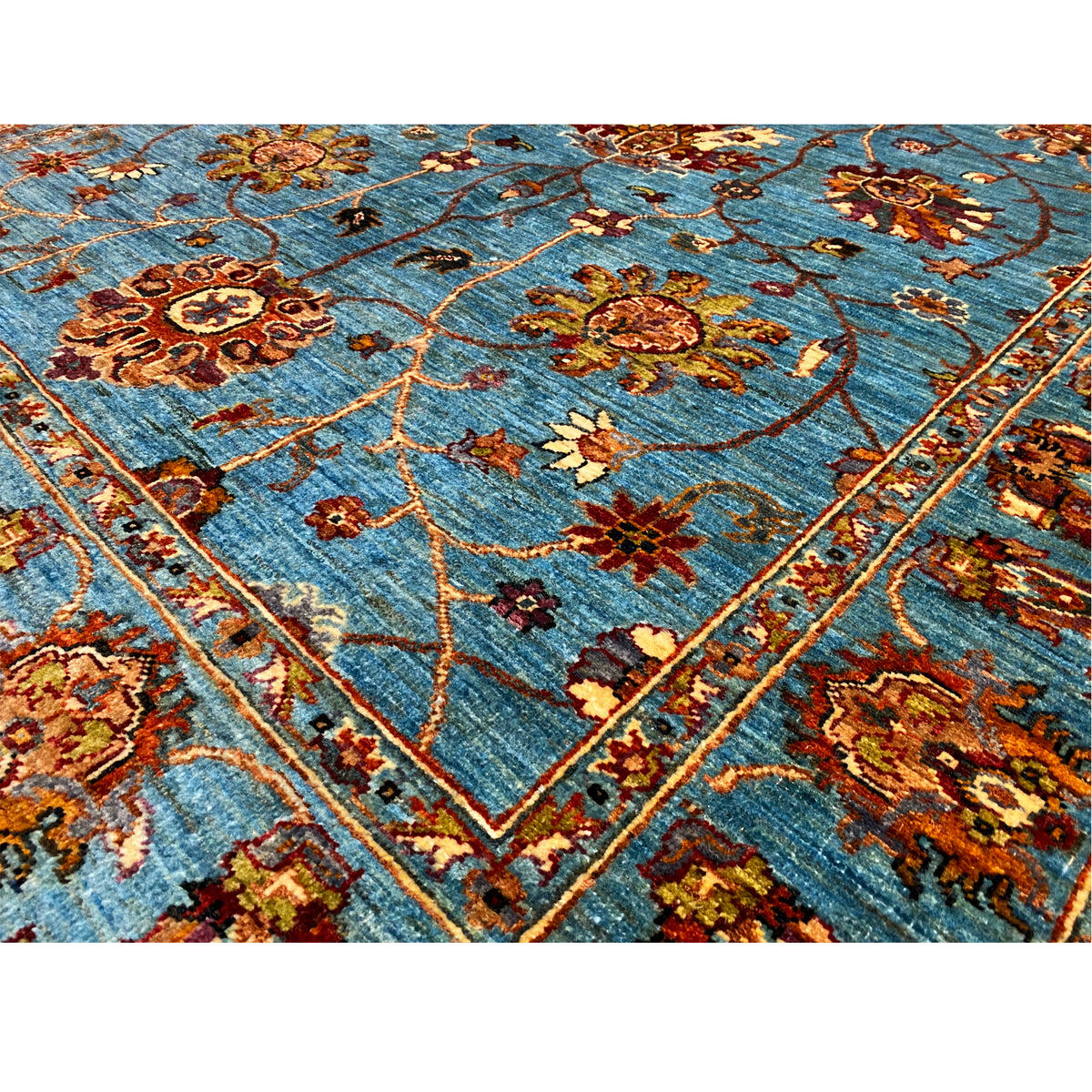 Blue Khorjin rug close-up: floral motifs, vine lines, and decorative border