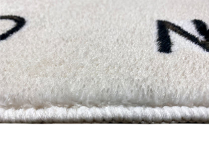 Kinderteppich-Detail: Flor und eingefasste Kante am Rand, mit schwarzer Schrift