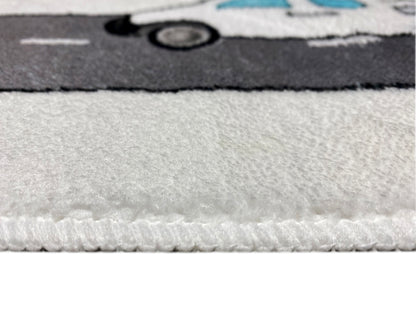 Kinderteppich-Detail am Rand: grauer Flor mit leichtem Stapel und farbigem Muster im Hintergrund.