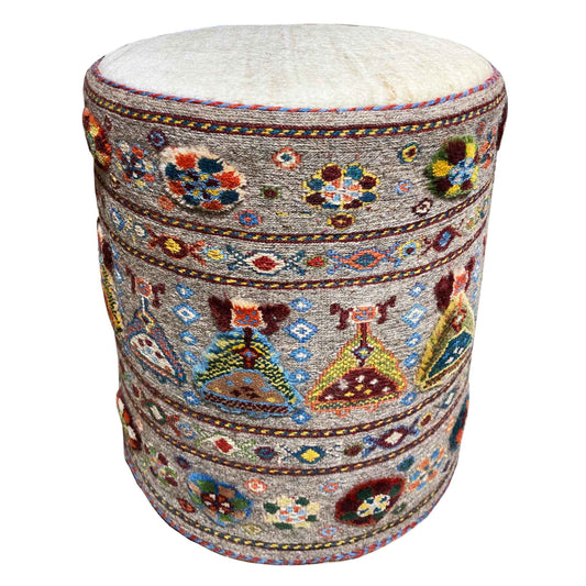 Round padded stool with light upholstery and a colorful ornamental pattern