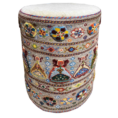 Round padded stool with a colorful ornamental pattern and light-colored upholstery