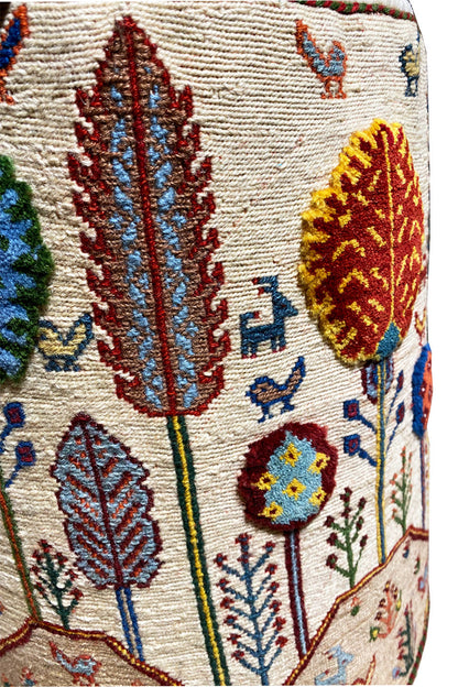 Close-up of the stool cover: embroidered leaves, blossoms, and small bird motifs on the fabric