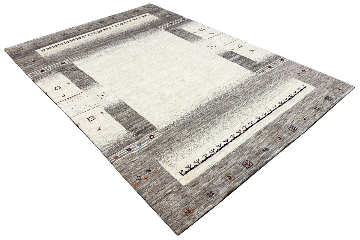 Gabbeh rug, photographed at an angle: light center with gray raw beams and decorations