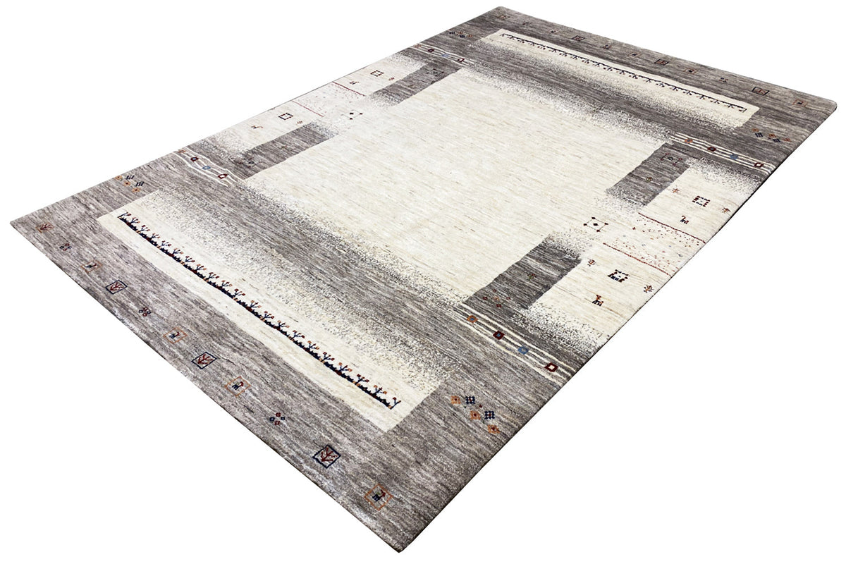 Gabbeh rug at an angle: light center, gray areas, small geometric accents