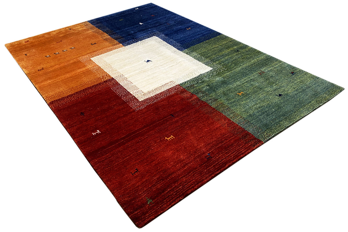 Gabbeh rug in angled view with a red, blue, green, and white central field