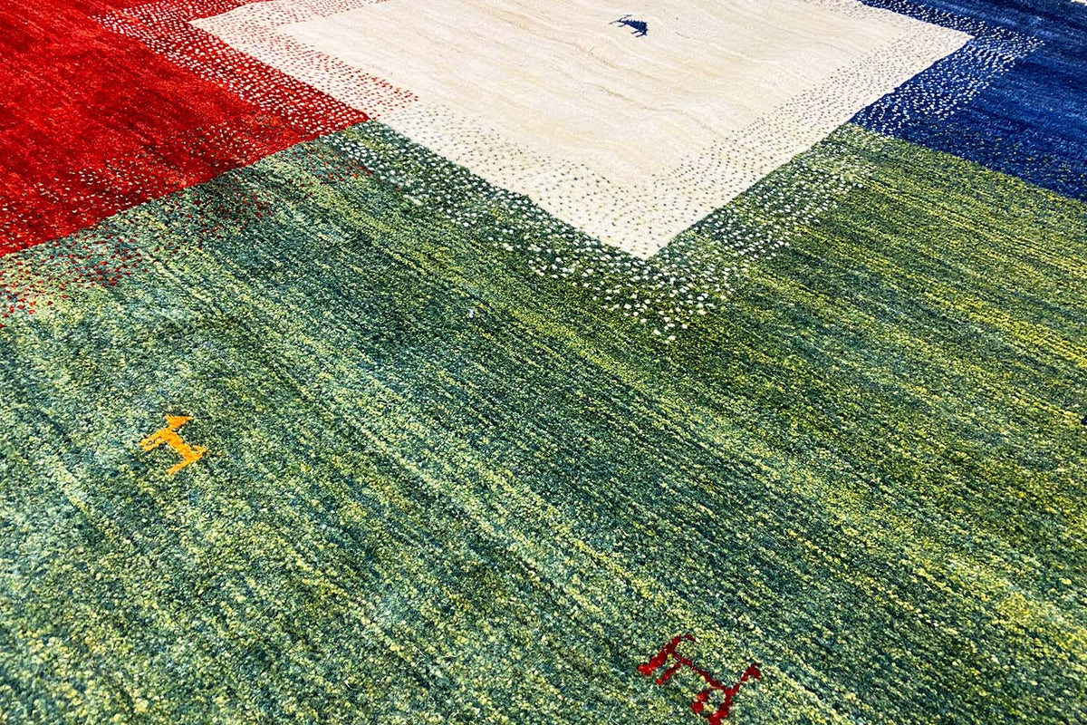 Close-up: greenish-gray Gabbeh rug with a light square and colorful accents